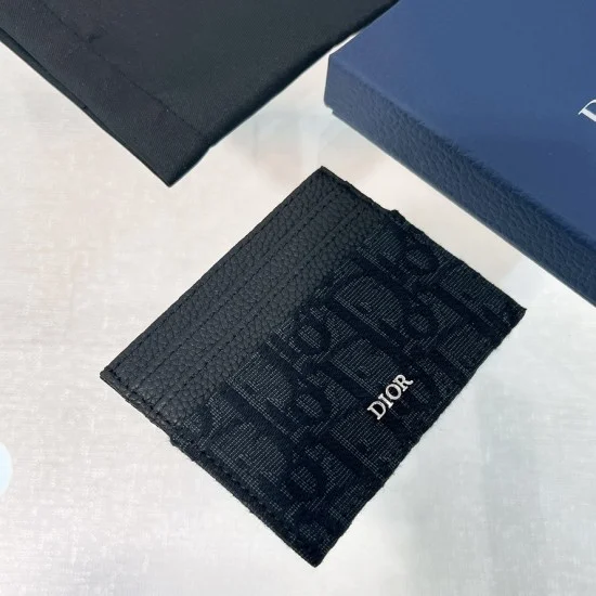 Men's Angled view of men card holder resting on surface next to packaging and pouch