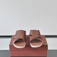 Frontal view of Loro Piana tabac brown ostrich leather slide sandals showcasing the criss-cross strap design