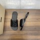 Top and angled view of black calfskin slides next to a branded box on a wooden surface in black and white