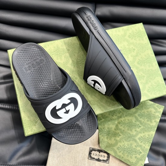 Gucci Men's Interlocking G Slide Sandals In Black Angled View in black and white Gucci Men's Interlocking G Slide Sandals In Black angled arrangement over patterned green boxes in black and white