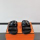 Hermes Jackson Sandals In Black Front View Hermes Jackson Sandals In Black front-facing view on top of packaging