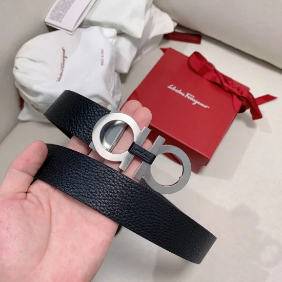 Hand holding Ferragamo Men's men Gancini belt with red gift box in background