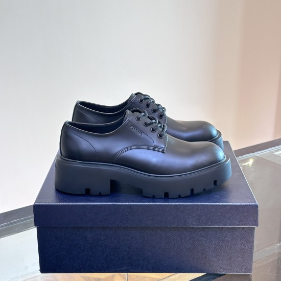 Prada Men's Brushed Leather Derby Shoes in black on shoebox Angle view of black Prada Men's Brushed Leather Derby Shoes resting on top of a branded blue shoebox