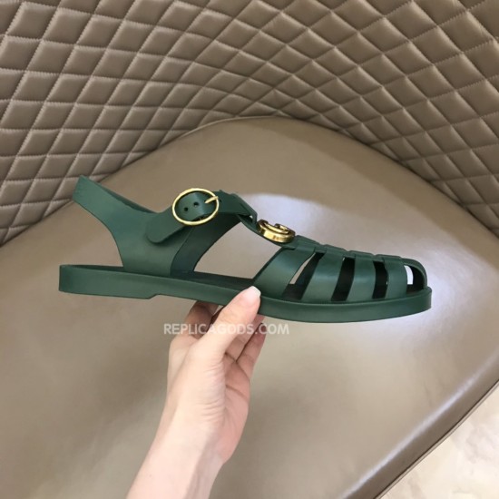 Gucci Green Rubber Sandal Lateral View Handheld lateral view of Gucci green rubber sandal on quilted background