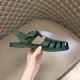 Gucci Green Rubber Sandal Lateral View Handheld lateral view of Gucci green rubber sandal on quilted background
