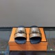 Hermes Gabriel brown and black sandals front angle view displaying metallic closures in brown and silver