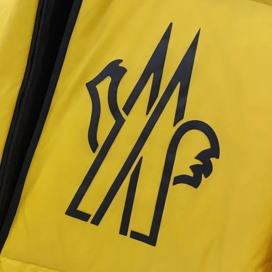 Moncler Men's Chest Logo Graphic Detail Close-up of Moncler Men's logo graphic print on yellow coat fabric