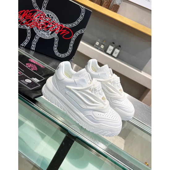 Side-angle view of Versace Odissea white leather trainers resting on display glass