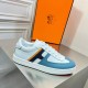 Lateral side view of Hermes Boomerang trainer showing white upper and blue panels