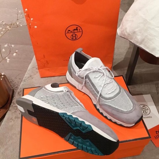 Pair of Hermes grey knit trainers displaying one outsole and one upper