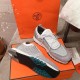 Pair of Hermes grey knit trainers displaying one outsole and one upper