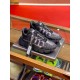 Versace Trigreca Black Trainers Three-Quarter Angle Three-quarter front view of a pair of black Versace Trigreca trainers on a glass shelf