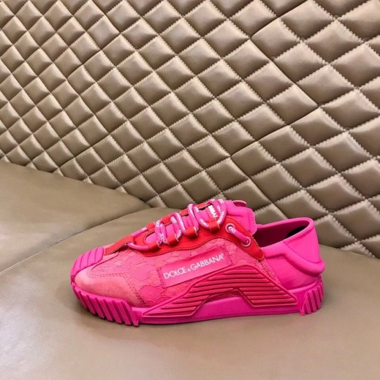 Dolce & Gabbana fuchsia pink lace slip-on trainer rested on a leather bench surface