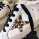 Golden Goose Leopard Star Detail in white and gold Close-up of Golden Goose white leather trainer showing leopard print star patch and black lace detail