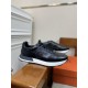 Hermes Drive Leather Low Top Trainers Black Angle View in black and white Perspective view of Hermes Drive Leather Low Top Trainer Black resting on wooden armrest in black and white