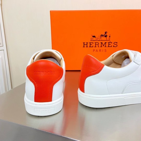 Rear view showing the orange leather heel tabs and embossed midsole branding on Hermès trainers in white and orange