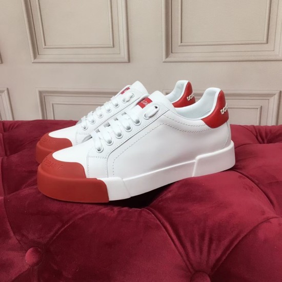 Pair of white leather trainers arranged on red tufted surface showing side and toe detail