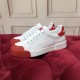 Pair of white leather trainers arranged on red tufted surface showing side and toe detail