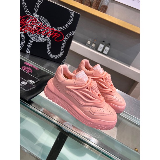Three-quarter view of the pair of pink Versace Odissea low top trainers resting on a glass display shelf