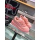 Three-quarter view of the pair of pink Versace Odissea low top trainers resting on a glass display shelf