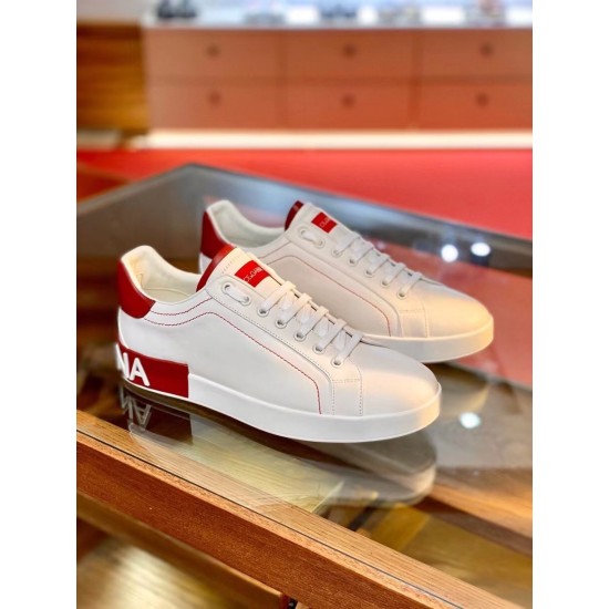 Pair of Dolce & Gabbana white and red Portofino trainers displayed on glass table