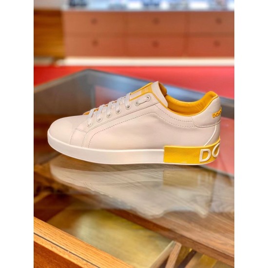 Lateral View of White Leather Portofino Trainer in white and yellow Lateral side view resting on glass surface showing white rubber sole and yellow trim