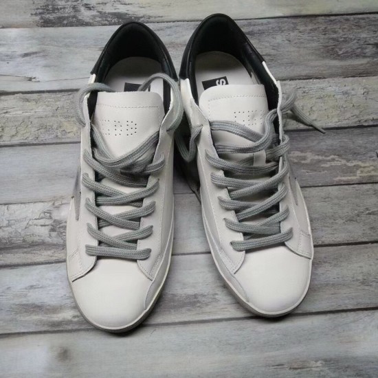 Golden Goose Super-Star Trainers - Pair Overhead View in white and grey Top-down view of a pair of Golden Goose Super-Star white leather trainers on wooden flooring in white and grey
