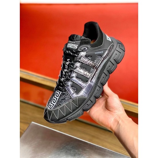 Versace Trigreca Black Trainer Close Up Handheld Hand holding a single black Versace Trigreca trainer highlighting the textured upper and Greca sole