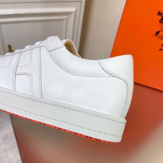 Hermes Boomerang Trainer White Leather Side Detail Close-up side view detailing the textured white leather stitching and orange outsole edge on the trainer.