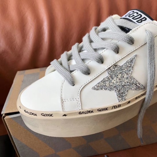 Close-up of Golden Goose trainer toe cap, grey laces, and silver glitter star emblem in white and silver