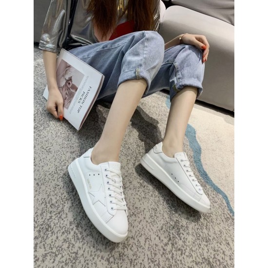 On-foot view of Golden Goose Purestar white leather trainers worn with denim jeans