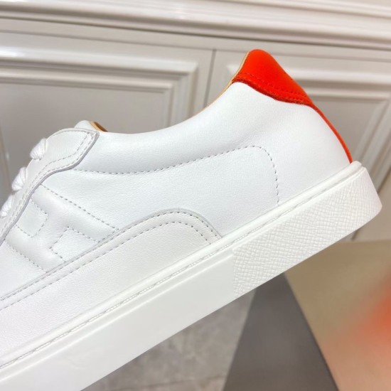 Detailed view of side stitching and white textured sole on Hermès leather trainer in white and orange
