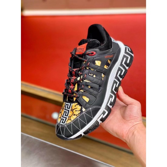Versace Trigreca Black Trainers Front Angle View in black and yellow Front oblique view held in hand displaying laced upper, Barocco print toe and red logo accents in black and yellow