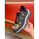 Versace Trigreca Black Trainers Front Angle View in black and yellow Front oblique view held in hand displaying laced upper, Barocco print toe and red logo accents in black and yellow