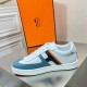 Side profile of Hermes Boomerang white trainer with blue accents and striping