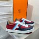 Pair of Hermes Boomerang trainers angled towards the camera beside orange shoe box in multicolour