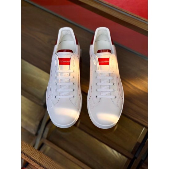Top-down overhead view of Dolce & Gabbana white leather trainers with red branded tongues