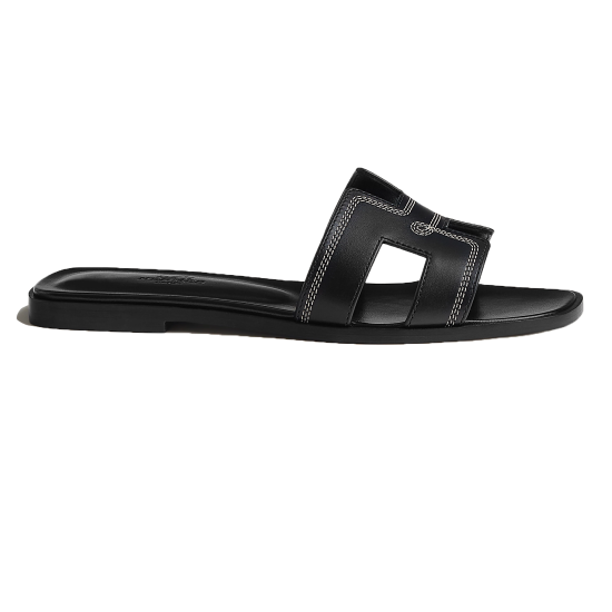 Side profile view of Hermes black sandals showing contrast stitching and flat sole