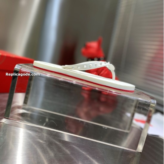 Christian Louboutin white spiked flat flip flop sandal resting on clear display stand