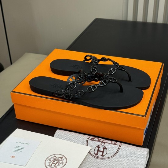 Hermes black Island Sandals angled presentation Angle view of Hermes black Island Sandals placed on top of an orange presentation box
