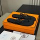 Hermes black Island Sandals angled presentation Angle view of Hermes black Island Sandals placed on top of an orange presentation box