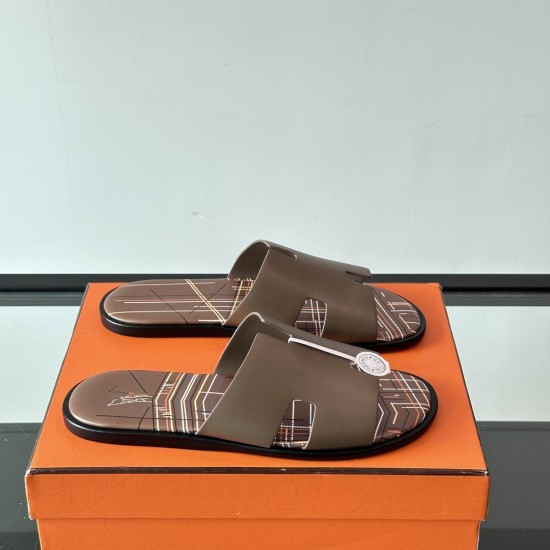 Hermes Izmir Sandals In Beige angled pair resting on an orange box