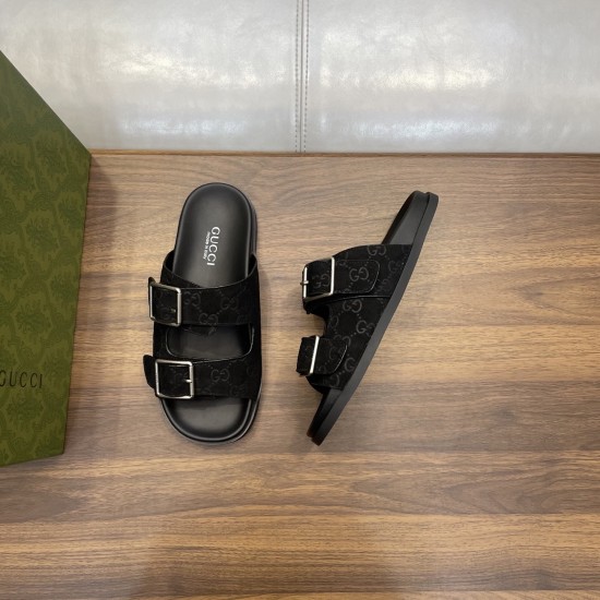 Angled top view of black Gucci slide sandals with branded insoles beside a green box in black and silver