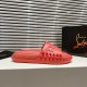 Side profile of stacked Christian Louboutin Take It Easy red mules next to a box