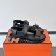 Hermes Black Sandals on Orange Box in black and white Lateral angle view of the black sandals resting on an orange box in black and white