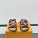 Front View Of Brown L Flat Mules Front facing view of the brown L Venice flat mules showcasing the cross straps