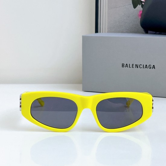 Balenciaga Women's Narrow Yellow Frame Sunglasses Front View Front view of Balenciaga Women's Narrow Yellow Frame Sunglasses resting on a surface with grey box background