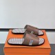 Angled view of Hermes Izmir Sandals in etoupe resting on an orange box