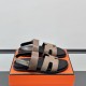 Hermes Genius Sandals in Etoupe Leather resting on an orange box in black