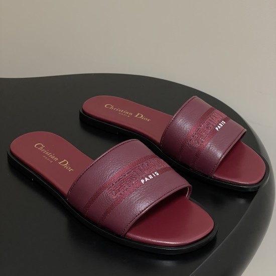 Angled Pair View of Dior Dway Burgundy Grained Calfskin Slides Angled pair view of the burgundy slides on a dark surface highlighting inner gold branding